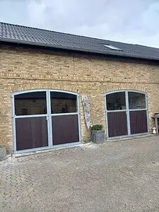 Staldporte med buet overkant og brune plastplanker